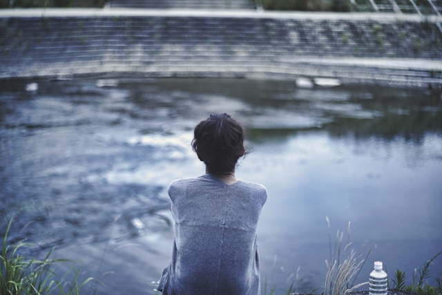女性の孤独な後ろ姿。家族を失ったご遺族の喪失感イメージ
